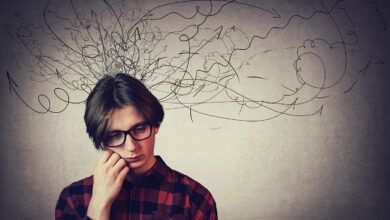 Closeup portrait of sad and thoughtful teen guy, hand under cheek, looking down feel headache, isolated on grey wall. Upset boy experiencing adolescence crisis as mess lines coming out of head.